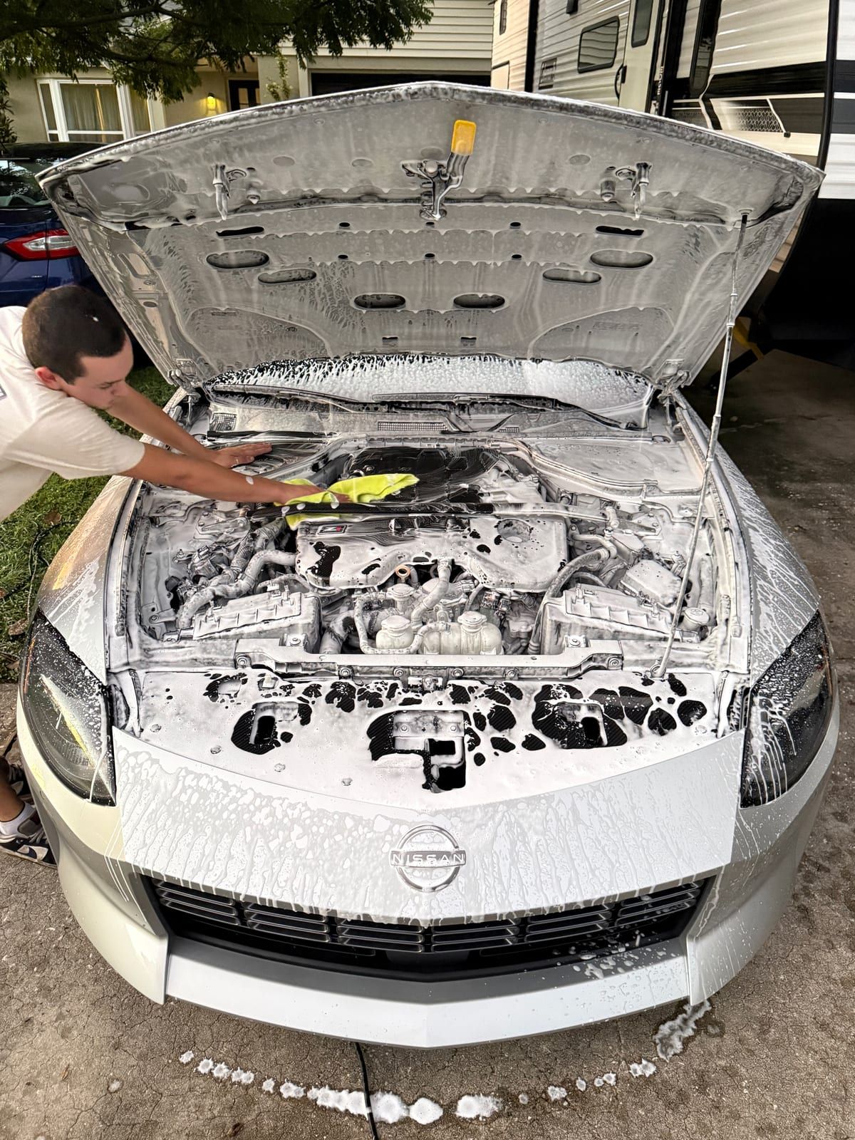 Detailer cleaning a foam-covered engine bay