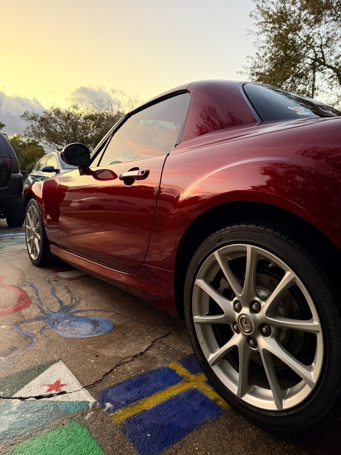 Reflective red coupe after paint correction at sunset