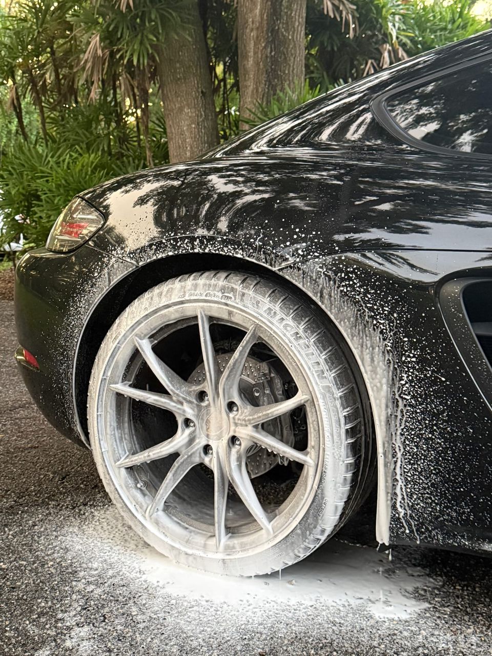 Foam-covered wheel and bodywork during a mobile detail